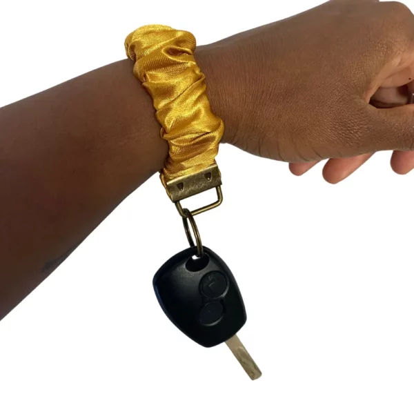 Scrunchie porta-chaves amarelo usado no pulso com chave