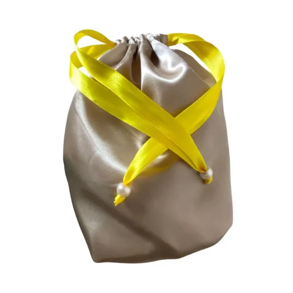 Saco de cetim dourado com fitas amarelas decorativas e pérolas, ideal para guardar a touca