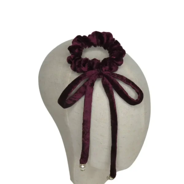 Scrunchie de veludo cor vinho com laço e pérolas usado como acessório de cabelo – estilo sofisticado.